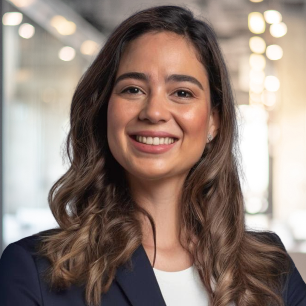 A professional headshot of a smiling woman in a dark blazer.