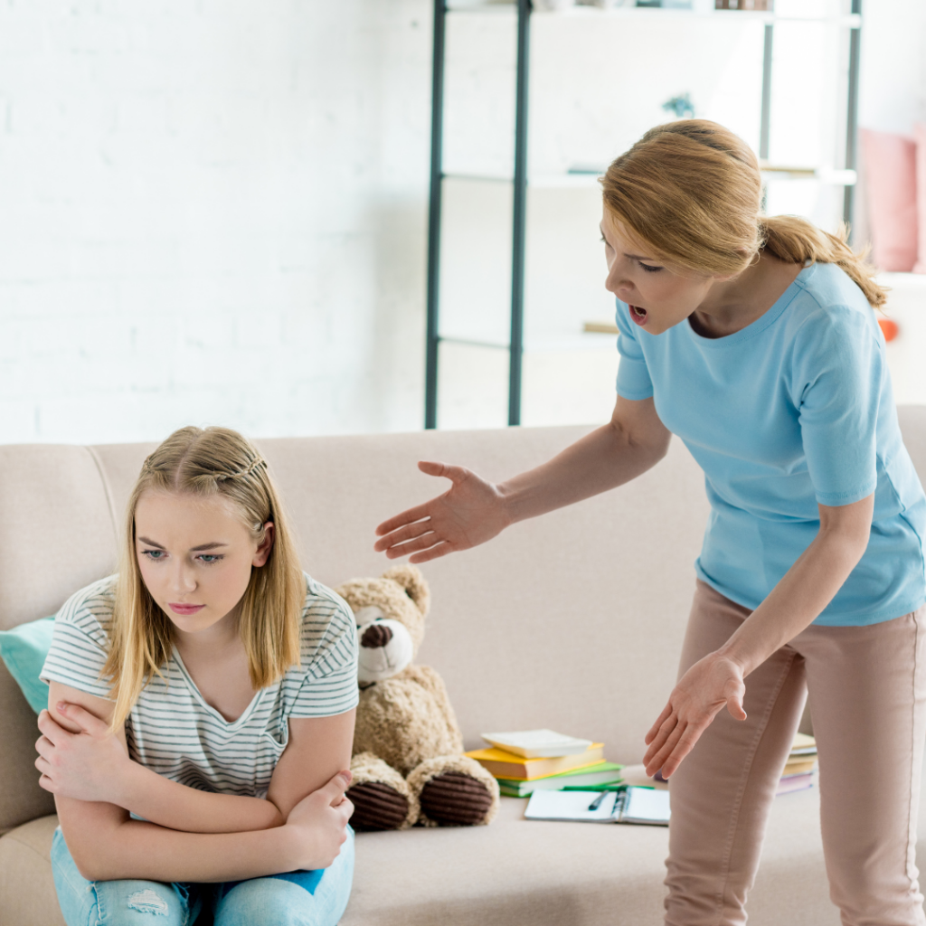 A woman gestures and shouts at a young girl sitting on a sofa with her arms crossed during a virtual anger management therapy session.